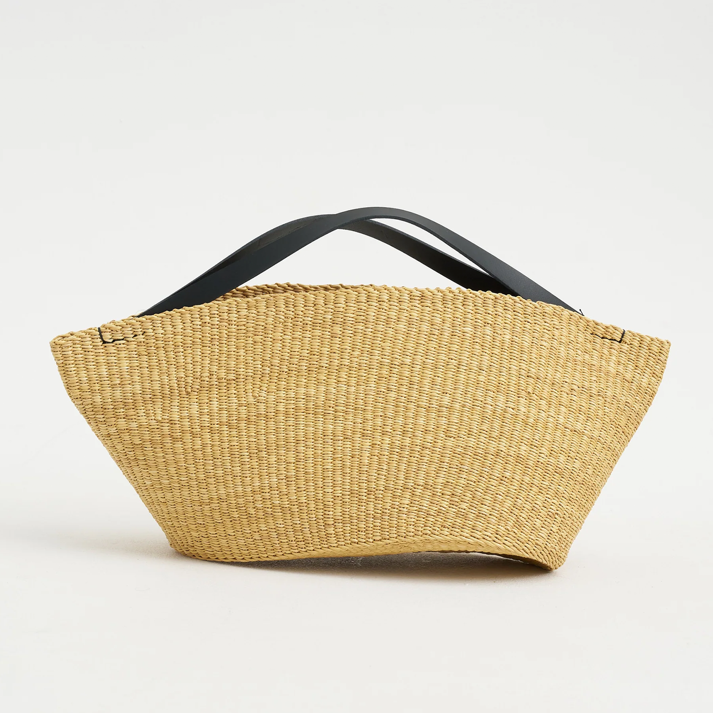 Natural Straw Asymmetrical Pinched Fan Shaped Tote With Smooth Curved Overhead Grip Strips, Wide Open Unsegmented Cavity And Soft Folded Base Silhouette