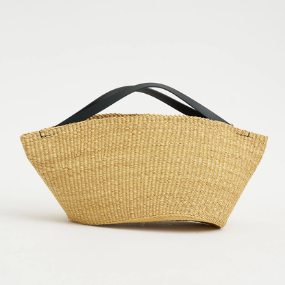 Natural Straw Asymmetrical Pinched Fan Shaped Tote With Smooth Curved Overhead Grip Strips, Wide Open Unsegmented Cavity And Soft Folded Base Silhouette